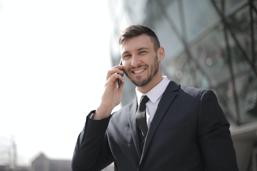 Smiling business professional holding a cell phone up to his ear.